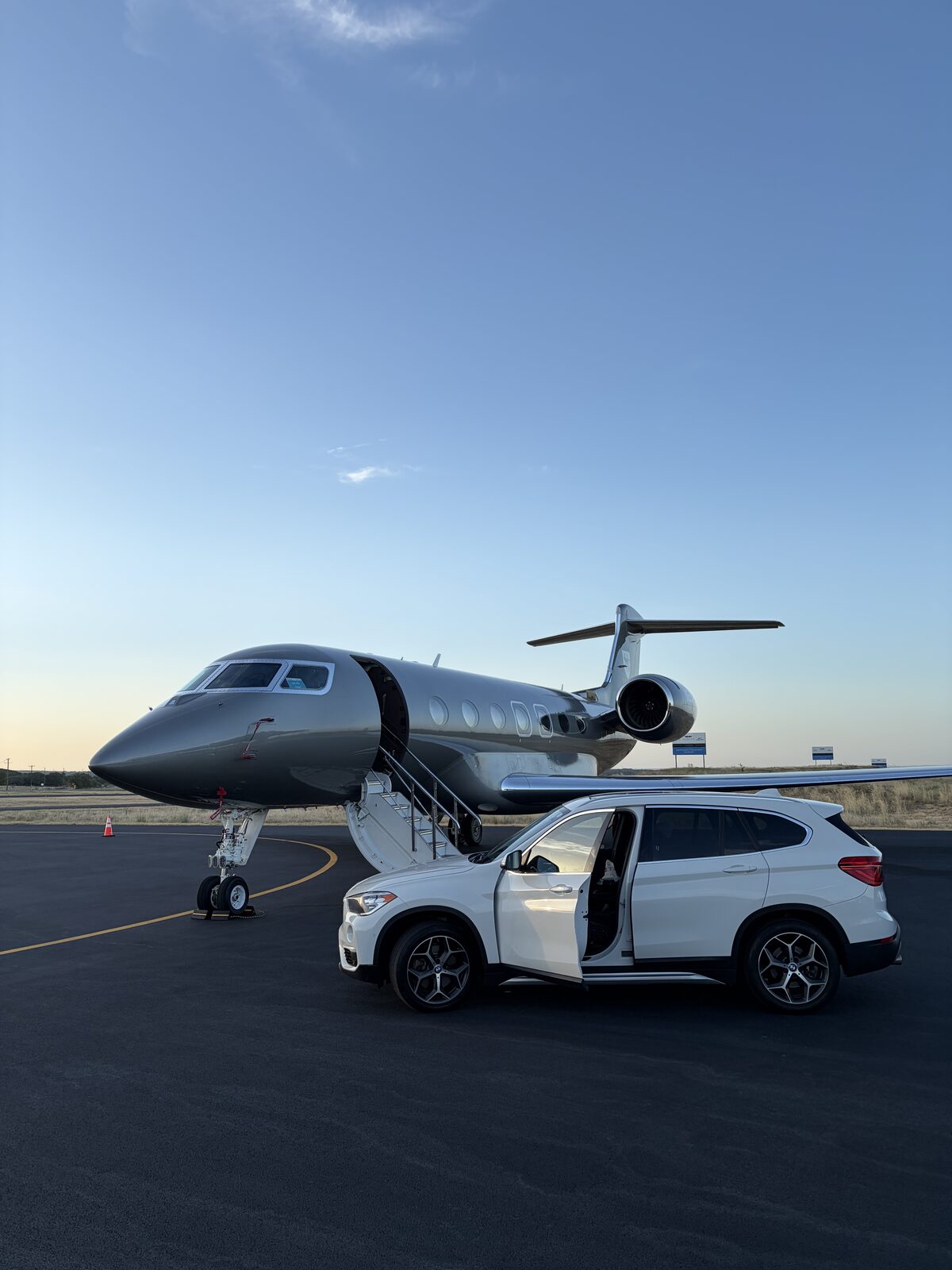 White BMW X1 rental parked beside a private jet at Granbury Regional Airport