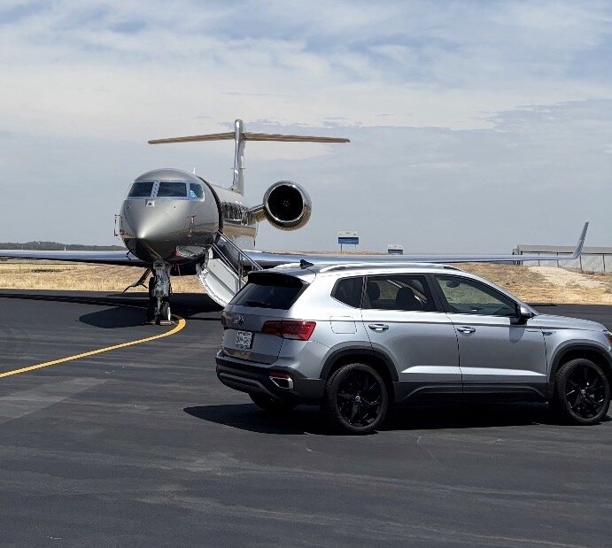 Silver 2024 Volkswagen Taos rental parked beside a private jet at Granbury Regional Airport